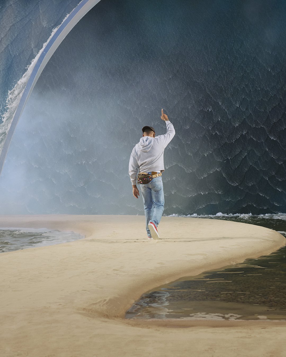 A man walking on a sandy path towards a massive artificial w